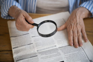 Ciudadano buscando con una lupa noticias en el periódico